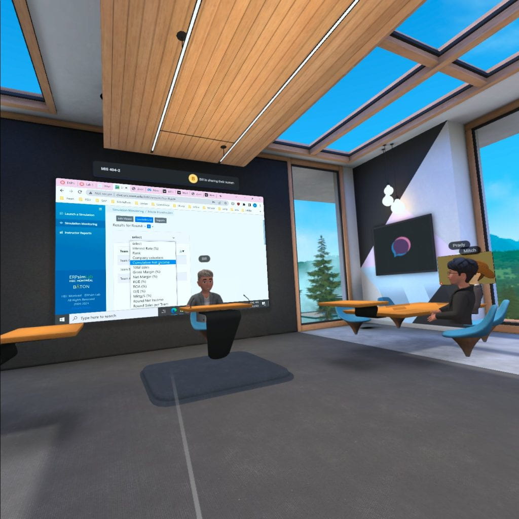 A virtual classroom with an avatar at the front behind a podium and two student avatars at virtual desks in front. A computer desktop screen is being shared on a large projector area behind the lecturer.