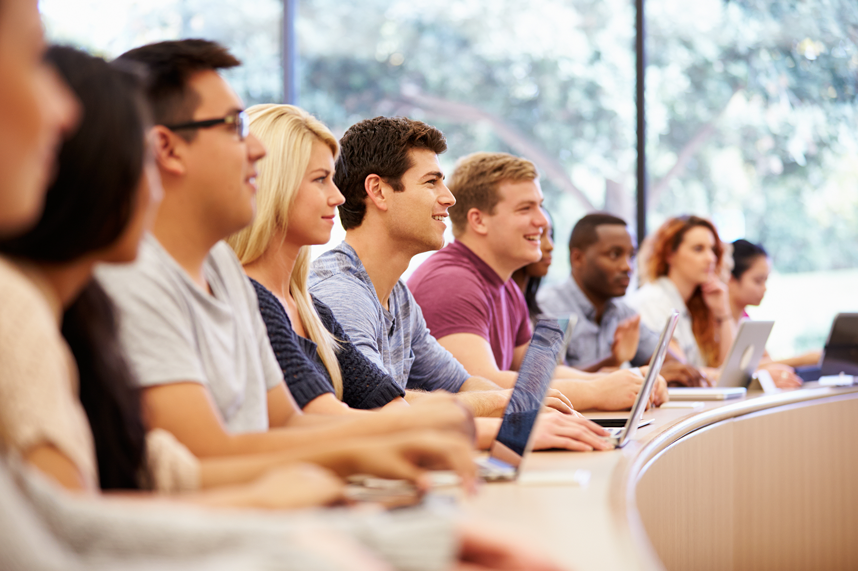 College students sitting at a curved desk, attending a lecture